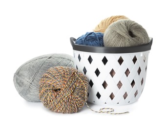 Basket with different balls of woolen knitting yarns on white background