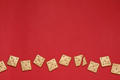 Photo of Golden cookies on red background, flat lay. Space for text
