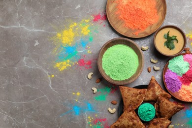 Traditional Indian food and color powders on grey table, flat lay with space for text. Holi festival celebration