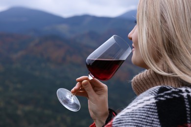 Young woman drinking wine in peaceful mountains, closeup