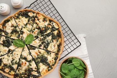 Photo of Delicious homemade quiche and fresh leaves on light gray table, flat lay. Space for text