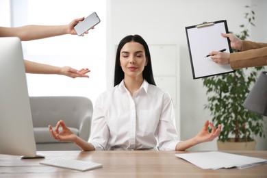 Photo of Overwhelmed woman meditating at workplace. Stress relief exercise