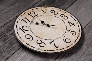 Photo of Clock showing five minutes until midnight on wooden table. New Year countdown