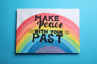 Photo of Painting with rainbow and life-affirming phrase Make Peace With Your Past on light blue background