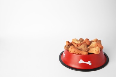 Photo of Bone shaped dog cookies in feeding bowl on white background, space for text