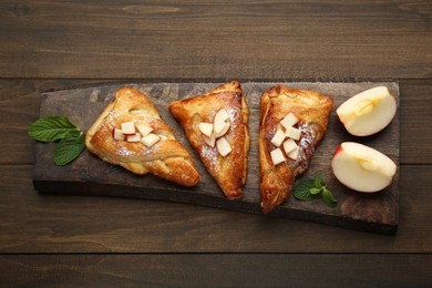Photo of Fresh tasty puff pastry with sugar powder, mint and apples served on wooden table, top view