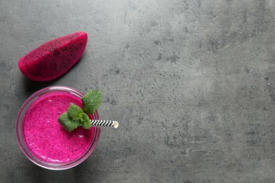 Glass of tasty pitahaya smoothie, fruit and fresh mint on grey table, flat lay. Space for text