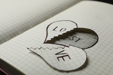 Broken heart with words LOVE and LOST in notebook, closeup. Relationship problems concept