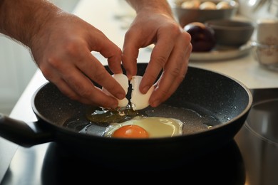 Man cooking eggs in frying pan, closeup