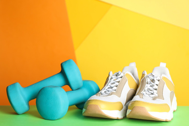 Dumbbells and modern sneakers on green table. Physical fitness