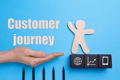 Image of Phrase Customer journey and woman holding hand to help human figure avoid trap with pencils as spikes on light blue background