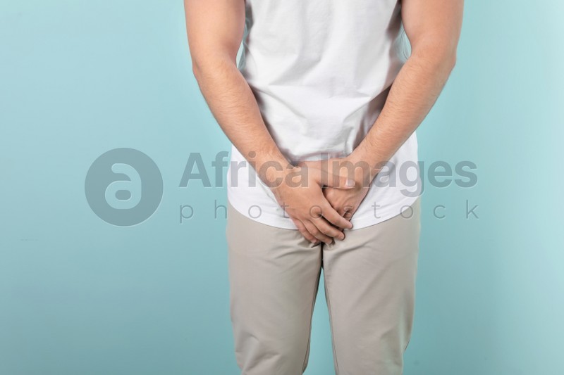 Young man with urological problems suffering from pain on color background