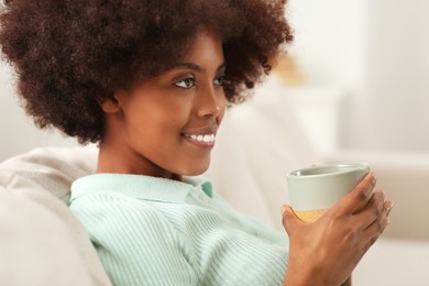 Photo of Smiling African American woman with cup of drink at home