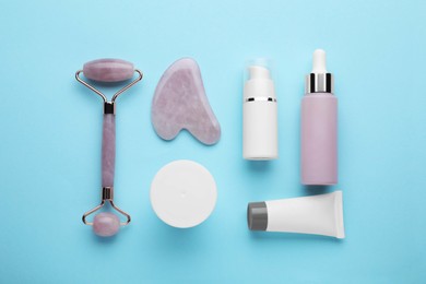 Flat lay composition with gua sha tool and, face roller and skin care products on light blue background