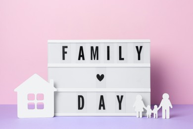 Photo of Lightbox with text Family Day, house model and people figure on violet table against pink background