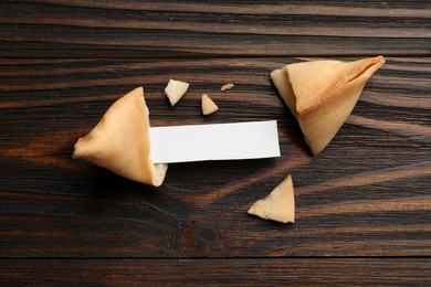 Photo of Tasty fortune cookie and paper with prediction on wooden table, flat lay. Space for text