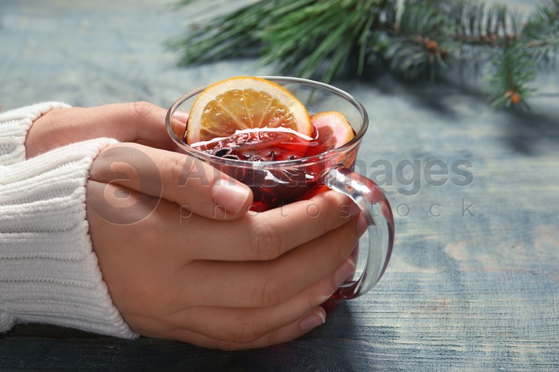 Woman holding cup with red mulled wine on table, closeup