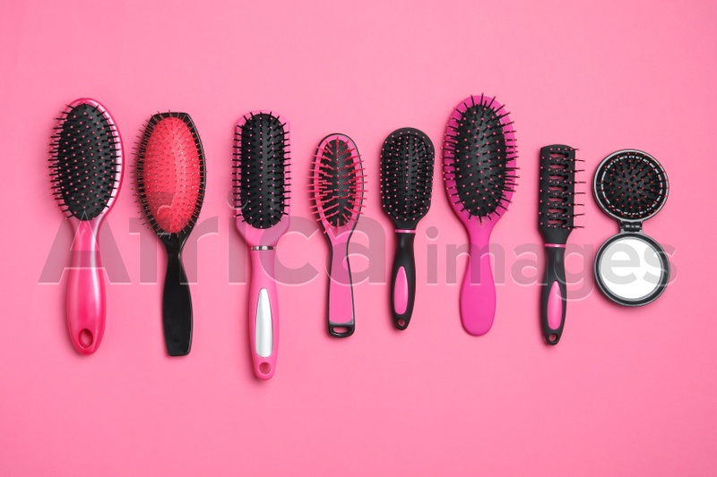 Flat lay composition with modern hair brushes on pink background