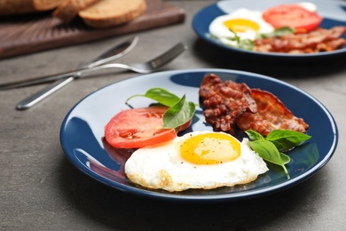 Fried sunny side up egg with tomato and bacon served on table