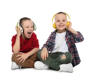 Portrait of cute twin brothers with headphones sitting on white background