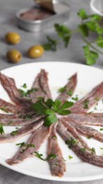 Photo of Plate with anchovy fillets and parsley on table, closeup