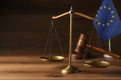 Scales of justice, judge's gavel and European Union flag on wooden table. Space for text