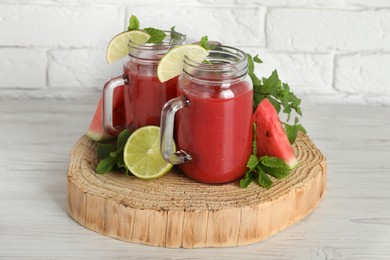 Photo of Tasty summer watermelon drink, limes and mint on white wooden table