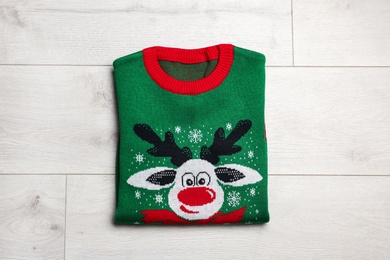 Photo of Folded warm Christmas sweater on wooden table, top view