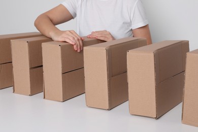 Woman folding cardboard boxes at white table, closeup. Production line