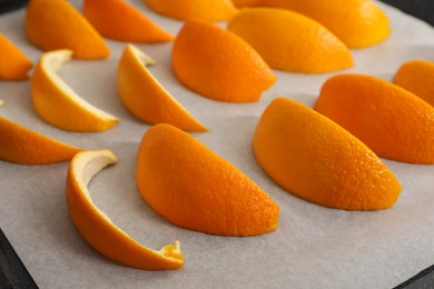 Photo of Fresh orange peels on white parchment paper, closeup