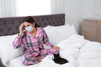 Young woman with cat suffering from allergy in bedroom