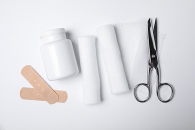 Bandage rolls and medical supplies on white background, flat lay