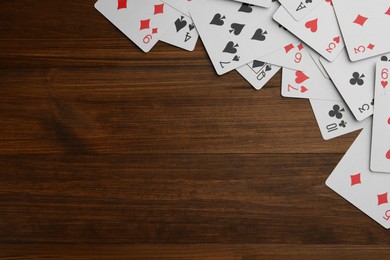 Photo of Playing cards on wooden table, flat lay. Space for text