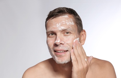 Man washing face with soap on white background