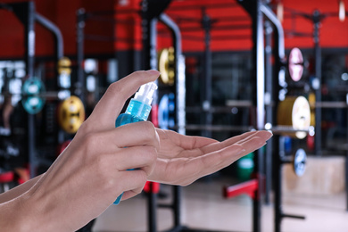 Woman applying antiseptic gel at gym, closeup. Preventive measures during epidemic period 
