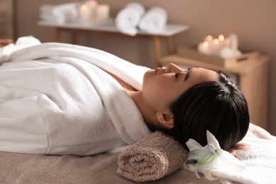 Beautiful Asian woman lying on massage table in spa salon