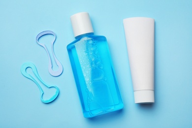 Tongue cleaners, mouthwash and tooth paste on color background, flat lay