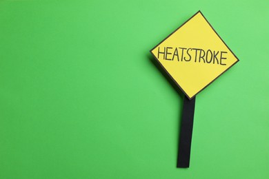 Sign with words Heat Stroke on green background, top view. Space for text
