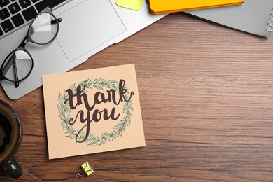 Card with phrase Thank You, laptop, glasses and notebooks on wooden table, flat lay. Space for text