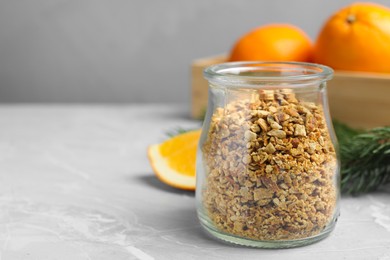 Photo of Jar of dried orange zest seasoning and fresh fruits on light grey table. Space for text