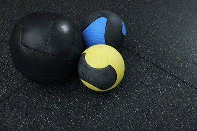 Many different medicine balls on black floor