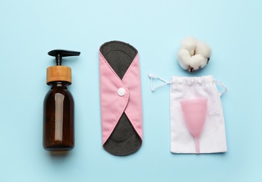 Flat lay composition with reusable cloth menstrual pad on light blue background. Female hygiene products