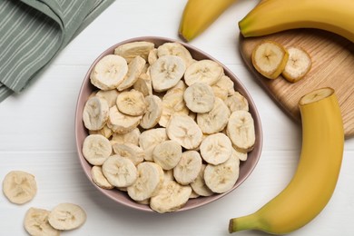 Freeze dried and fresh bananas on white wooden table, flat lay