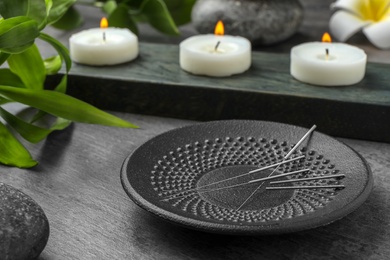 Plate with acupuncture needles on table