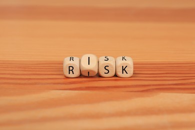 Cubes with word Risk on wooden table, closeup