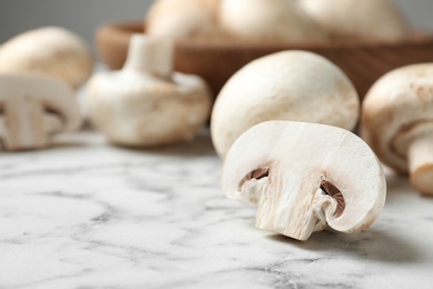 Fresh champignon mushrooms on marble table, closeup. Space for text