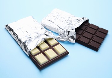 Photo of Tasty chocolate bars on light blue background