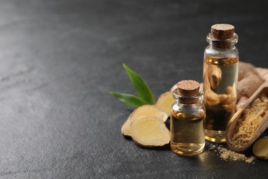 Glass bottles of essential oil, ginger powder and root on dark table, space for text