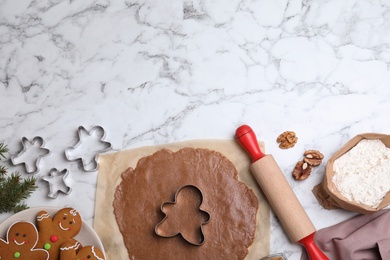 Flat lay composition with homemade gingerbread man cookies on white marble table, space for text