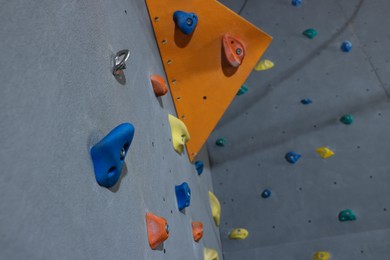 Climbing wall with holds in gym, low angle view. Extreme sport
